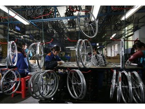 FILE - In this March 4, 2011, file photo, workers from the Dahon, the world's largest maker of folding bicycles, assembles the bicycle wheels in Shenzhen, a city of southern China. The latest round of China tariff hikes, which went into effect Friday, May 10, 2019. will hit a range of consumer goods, including bicycles, luggage, furniture and seafood.