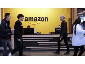 FILE - In this Nov. 13, 2018 file photo, employees walk through a lobby at Amazon's headquarters in Seattle. On Friday, May 3, 2019, shares in Amazon are moving higher after billionaire investor Warren Buffett said his firm has been buying the online retailer.