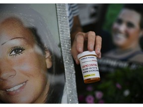 FILE - In this Friday, Aug. 17, 2018, file photo, a demonstrator holds a prescription drug bottle with a mock label to protest Purdue Pharma and its product, OxyContin, outside the company's headquarters in Stamford, Conn. The protest was organized by those who have lost loved ones in the opioid epidemic.