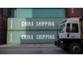 FILE- In this July 5, 2018, file photo, a jockey truck passes a stack of 40-foot China Shipping containers at the Port of Savannah in Savannah, Ga. For months, the U.S. economy has shrugged off the tariffs slapped by America and China on tens of billions of dollars of each other's goods.