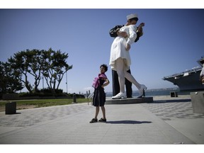 FILE - In this Sept. 18, 2015, file photo a tourist from China stands in front of the sculpture "Unconditional Surrender," in San Diego. Travel from China to the U.S. fell 4.6 percent in the first 10 months of 2018 compared to the same period the prior year, according to U.S. government data. The government hasn't released full-year figures yet, but if the trend holds, it will be the first time since 2003 that Chinese travel to the U.S. fell from the prior year.