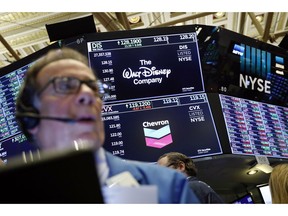 FILE - In this April 12, 2019, file photo the logos for The Walt Disney Company and Chevron appear above a trading post on the floor of the New York Stock Exchange. The Walt Disney Company reports financial results Wednesday, May 8.