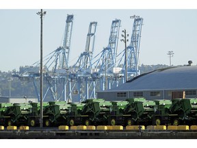 FILE - In this May 10, 2019, file photo John Deere Agricultural machinery made by Deere & Company sits staged for transport near cranes at the Port of Tacoma in Tacoma, Wash. Deere's fiscal second-quarter earnings were a mixed bag and the agricultural equipment maker lowered its full-year outlook as the trade war between the U.S. and China intensifies and conditions in the agricultural sector soften.