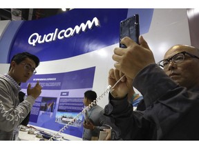 FILE - In this Nov. 6, 2018 file photo, attendees look at the latest technology from Qualcomm at the China International Import Expo in Shanghai. Qualcomm's stock is tumbling before Wednesday's market open on May 22, 2019, after a federal judge ruled that the company unlawfully stifled cellphone chip market competition and charged excessive licensing fees.