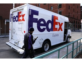 FILE - In this March 17, 2017, photo, a FedEx driver returns to his truck in downtown Pittsburgh.  FedEx plans to deliver packages seven days a week starting next January 2020 as it tries to keep up with the continuing boom in online shopping.  The Memphis, Tennessee-based company announced the moves Thursday, May 30, 2019.