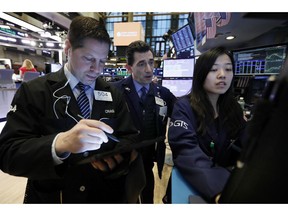 FILE - In this March 18, 2019, file photo trader Craig Esposito, left, works with specialists Peter Mazza, center, and Vera Liu on the floor of the New York Stock Exchange. The U.S. stock market opens at 9:30 a.m. EDT on Thursday, May 2.