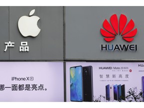 FILE - In this Thursday, March 7, 2019, file photo, logos of Apple and Huawei are displayed outside a mobile phone retail shop in Shenzhen, China's Guangdong province. Few U.S. companies are more vulnerable to a trade war with China than Apple. The Trump administration's decision to bar U.S. technology sales to Huawei, one of China's leading brands, might put Apple in the crosshairs.