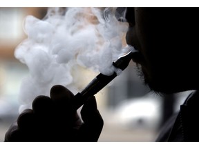 FILE - In this April 23, 2014, file photo, a man smokes an electronic cigarette in Chicago. In a ruling handed down Wednesday, May 15, 2019, a federal judge is siding with public health groups in their effort to force the Food and Drug Administration to begin reviewing the health effects of e-cigarettes.