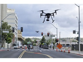 In this May 21, 2019 photo, two drones fly above Lake Street in downtown Reno, Nev., on, as part of a NASA simulation to test emerging technology that someday will be used to manage travel of hundreds of thousands of commercial, unmanned aerial vehicles (UAVs) delivering packages. It marked the first time such tests have been conducted in an urban setting.