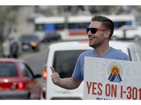 Chris Olson gives drivers a thumbs-up near a busy intersection in downtown Denver on Monday, May 6, 2019, as he urges voters to decriminalize the use of psilocybin, the psychedelic substance in "magic mushrooms." Voters will decide Tuesday whether Denver will become the first U.S. city to decriminalize the drug.