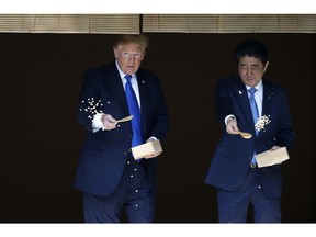 FILE - In this Nov. 6, 2017, file photo, U.S. President Donald Trump, left, and Japanese Prime Minister Shinzo Abe feed carp before their working lunch at Akasaka Palace in Tokyo. Trump's Japan visit starting on Saturday, May 25, 2019, is to focus on personal ties with Abe rather than substantive results on trade, security or North Korea.