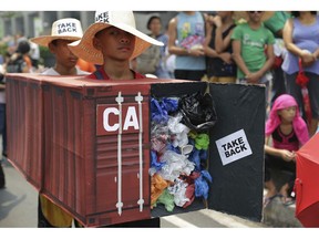 FILE - In this May 7, 2015, file photo, Filipino environmental activists wear a mock container vans filled with garbage to symbolize the 50 containers of waste that were shipped from Canada to the Philippines two years ago, as they hold a protest outside the Canadian embassy at the financial district of Makati, south of Manila, Philippines. The Philippine foreign secretary said Thursday, May 16, 2019, the ambassador and consuls in Canada are being recalled over Ottawa's failure to take back truckloads of garbage that Filipino officials say were illegally shipped to the Philippines years ago.