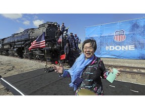 Margaret Yee, whose ancestors helped build the railroad, pose in front of the the Big Boy, No. 4014 during the commemoration of the 150th anniversary of the Transcontinental Railroad completion at Union Station Thursday, May 9, 2019, in Ogden, Utah. Yee, helped tap a ceremonial spike alongside Utah Gov. Gary Herbert and a descendant of Union Pacific's chief engineer on the project at the event Thursday in Ogden, Utah.