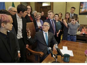 Washington Gov. Jay Inslee, center, turns to talk with Katrina Spade, upper left, the founder and CEO of Recompose, a company that hopes to use composting as an alternative to burying or cremating human remains, Tuesday, May 21, 2019, at the Capitol in Olympia, Wash., before signing a bill into law that allows licensed facilities to offer "natural organic reduction," which turns a body, mixed with substances such as wood chips and straw, into soil in a span of several weeks. The law makes Washington the first state in the U.S. to approve composting as an alternative to burying or cremating human remains.