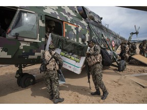 In this April 1, 2019 photo, returning to their home base soldiers load their television in to a military helicopter, on a makeshift airstrip at the Balata military and police base in Peru's Tambopata province.