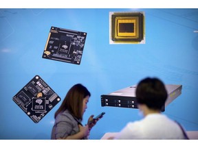 FILE - In this May 18, 2018, file photo, visitors walk past a display showing microchips and circuit boards at the 21st China Beijing International High-tech Expo in Beijing. For four decades, Beijing has cajoled or pressured foreign companies to hand over technology. And its trading partners say if that didn't work, China stole what it wanted.