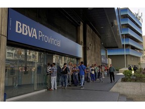 Customer line up outside a branch of Banco Provincial bank in Caracas, Venezuela, Monday, May 13, 2019. After 16 years of currency controls, the government is allowing its Bolivar to be exchanged on the floating market starting Monday, starting at 5,200 Bolivars per U.S. dollar.