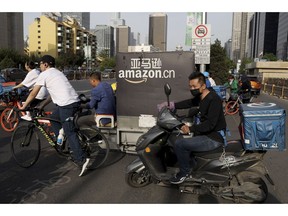 In this Wednesday, May 8, 2019, photo, a delivery man bearing U.S. commerce giant Amazon's brand is seen in downtown Beijing. China said Thursday it will retaliate if President Donald Trump goes ahead with more tariff hikes in a fight over technology and trade, ratcheting up tensions ahead of negotiations in Washington.