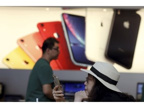 A customer looks at her iPhone in a store of U.S. tech company Apple in Beijing on Friday, May 10, 2019. U.S. President Donald Trump's latest tariff hike on Chinese goods took effect Friday and Beijing said it would retaliate, escalating a battle over China's technology ambitions and other trade tensions.