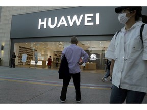 In this photo taken Monday, May 20, 2019, a man stands outside a Huawei store in Beijing. The Financial Times reported Friday, May 31, 2019 that tech giant Huawei has ordered its employees to cancel technical meetings with American contacts and has sent home numerous U.S. employees working at its Chinese headquarters.