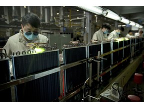 In this Feb. 24, 2017, photo, factory workers use gas torches on air conditioning condenser units on an assembly line at a Haier factory in Jiaozhou near Qingdao in eastern China's Shandong Province. U.S. President Donald Trump's latest tariff hike on Chinese goods took effect Friday, May 10, 2019, and Beijing said it would retaliate, escalating a battle over China's technology ambitions and other trade tensions.