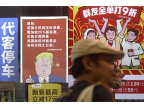 FILE - In this Aug. 13, 2018, file photo, a man walks by a poster depicting a mural of U.S. President Donald Trump stating that all American costumers will be charged 25 percent more than others starting from the day president Trump started the trade war against China, on display outside a restaurant in Guangzhou in south China's Guangdong province. What do tilapia, Jane Austen and revolutionary posters have in common? All have been used in recent days to rally public support around China's position in its trade dispute with the U.S., as the ruling Communist Party takes a newly aggressive approach to controlling the narrative and stirring up nationalistic sentiment. (Color China Photo via AP, File)