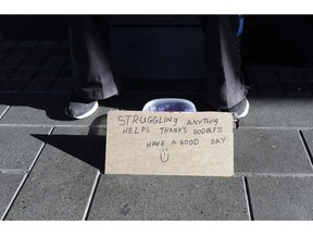 A man sits with a bowl asking for money in the central business district of Christchurch, New Zealand, Thursday, May 30, 2019. The liberal-led government on Thursday unveiled the country's first so-called well-being budget, which aims to measure social outcomes like health and the environment alongside traditional metrics such as economic growth.