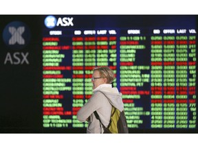 A woman looks at display boards at the Australian Stock Exchange in Sydney, Australia, Monday, May 6, 2019. Shares tumbled in Asia after President Donald Trump threatened to impose more tariffs on China, spooking investors who had been expecting good news this week on trade.