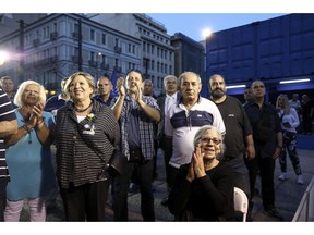 Supporters of New Democracy opposition conservative party react as they watch an exit poll at a campaign kiosk, in Athens, Sunday, May 26, 2019. New Democracy party is projected to win the European election, according to an exit poll jointly conducted by five Greek polling firms.