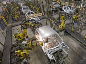 Robots weld the bodywork of new cars on an assembly line.