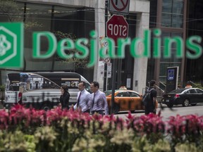 Pedestrians are seen reflected in the window of a Desjardins Group building in Toronto.