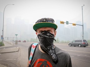 A man wears a bandana over his face as the Calgary skyline fills with smoke from the wildfires burning in northern Alberta.
