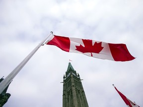 A Canadian flag in front of the peace tower on Parliament Hill.