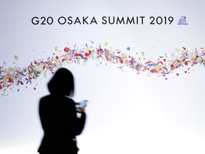 A woman walks past signage for the Group of 20 (G20) summit in Osaka, Japan, on Friday, June 28, 2019.