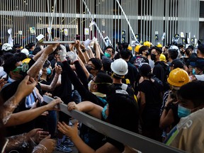 Demonstrators remove metal bars from a fence outside the Legislative Council building during a protest in Hong Kong, China, on Monday, July 1, 2019. Hong Kong's chief executive condemned protesters who occupied and ransacked the city's legislative chamber on Monday in an escalation of demonstrations against the China-appointed government, prompting police to fire tear gas to clear the area.