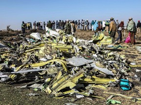 In this photo from March 11, 2019, people stand near collected debris at the crash site of Ethiopia Airlines near Bishoftu, a town some 60 km southeast of Addis Ababa, Ethiopia.