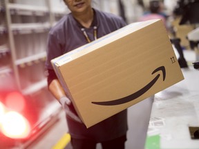 An employee carries a box at the Amazon.com Inc. fulfilment centre in Tilbury, U.K.