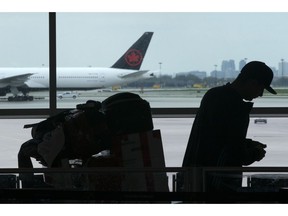 A passenger waits beside their luggage at the departure terminal at Toronto Pearson Airport, in Mississauga, Ont., Friday, May 24, 2019. Starting today, airline passengers can receive up to $2,400 if they'e bumped from a flight, part of a slew of air traveller protections beefing up compensation for travellers subjected to delayed flights and damaged luggage.
