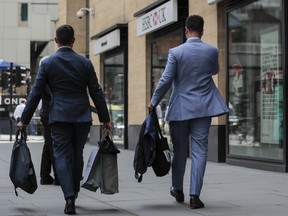 Men carry bags and suit carriers as they leave the offices of Deutsche Bank AG in London, U.K., on Monday.