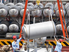 Employees work next to tanks for liquefied natural gas (LNG) at a factory in Xian, Shaanxi province, China.