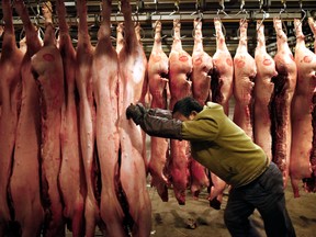 Workers examine and move pig carcasses at a meat wholesale and distribution centre in Shanghai, China.