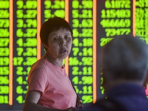 An investor talks in front of a screen showing stock prices at a securities company in Hangzhou in China's eastern Zhejiang province on August 6, 2019.