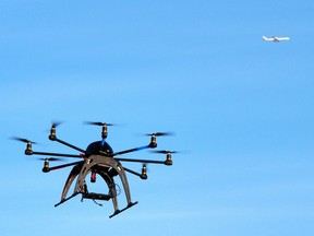 This file photo taken on February 1, 2014 shows a small remote-controlled drone hovering in the sky as an airliner flies by on February 1, 2014 during a meet-up of the D.C. Area Drone User Group.