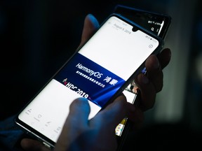 A guest holds her phone showing a picture taken during Huawei's press conference unveiling its new HarmonyOS operating system in Dongguan, Guangdong province on August 9, 2019. Chinese telecom giant Huawei unveiled its own operating system on August 9, as it faces the threat of losing access to Android systems amid escalating US-China trade tensions.