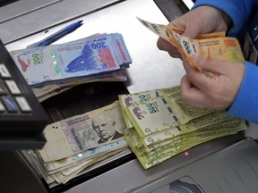 A cashier counts Argentine pesos bills at a supermarket in Buenos Aires on August 15, 2019.