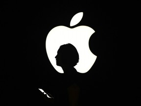 In this file photo taken on September 9, 2015 a reporter walks by an Apple logo during a media event in San Francisco, California.