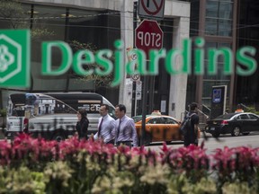 Pedestrians are seen reflected in the window of a Desjardins Group building in Toronto.