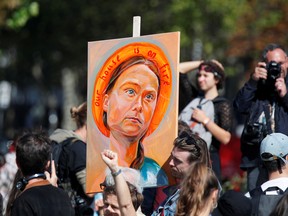 A man holds a painting titled "Our House Is On Fire (Our Children Will Burn)" by artist Julia Vanderbyl depicting Swedish climate activist Greta Thunberg, during the Fridays for Future climate change action protest in Paris, France, September 20, 2019.