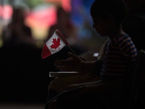 A new Canadian holds a flag at a citizenship ceremony in Windsor, Ont.