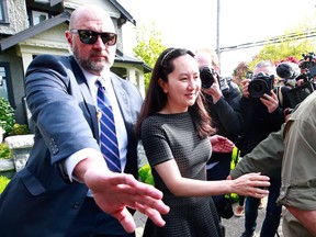 Huawei Technologies Chief Financial Officer Meng Wanzhou is escorted by security as she leaves her home on May 7, 2019 in Vancouver.